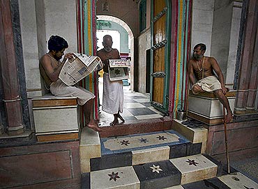 Priests read newspapers inside a temple in Ayodhya