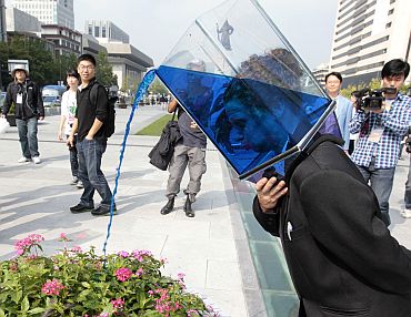A performer wearing a transparent box with water pours water on flowers as she wanders around the street during her group's street performance 'Waterheads', as a part of the Hi Seoul Festival 2010 in central Seoul. The performance was created and performed by Australian street performance group Erth