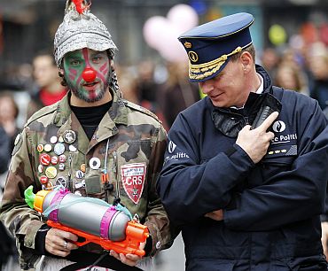 A Belgian police officer looks at a water gun carried by an activist disguised as a clown during a protest against the European Union's anti-migration policy in central Brussels on October 2