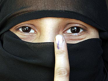 A Muslim woman shows her ink-marked finger after voting