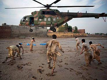 Flood victims rush to a military helicopter distributing aid