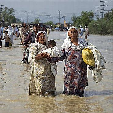 Two displaced Pakistani women wade through knee-deep water