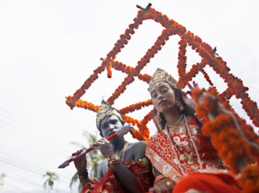 Children dressed as Lord Krishna and goddess Radha participate in a rally