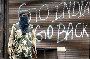 A policeman stands guard near a closed shop during a curfew in Srinagar