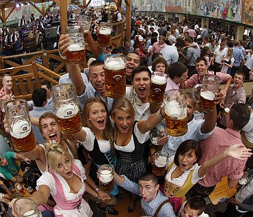 People wearing traditional Bavarian clothes toast with beer