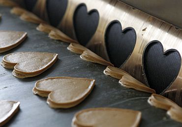 Gingerbread dough for traditional Oktoberfest hearts pass along a conveyor belt after being cut out