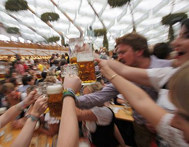 People wearing traditional Bavarian clothes toast with beer during the opening day of the 177th Oktoberfest