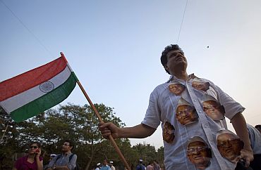 A demonstrator wearing portraits of social activist Anna Hazare on his shirt carries the national flag during a protest rally against corruption in Mumbai