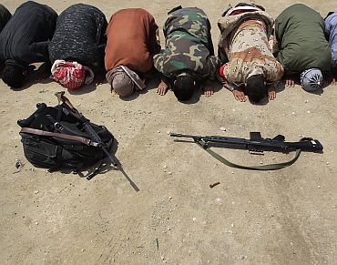 Rebel fighters pray at the front line along the western entrance of Ajdabiyah