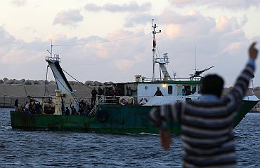 A Libyan man waves at a fishing boat carrying evacuees from Misrata at the port of Benghazi