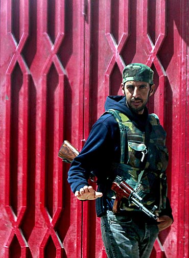 A rebel fighter stands guard along a street in the town of Ajdabiya