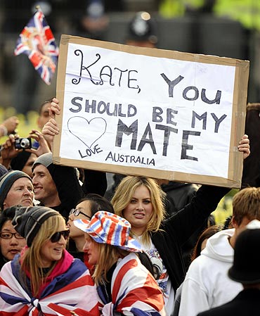 A woman holds a sign as crowds gather outside Buckingham Palace