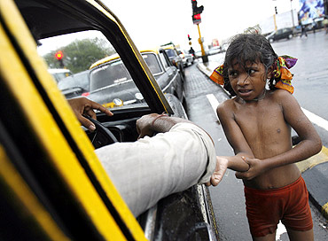 A little girl begs for alms in the rain in Mumbai