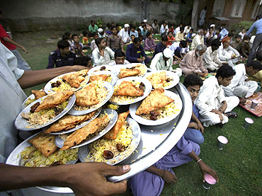 A man walks with a tray of donated food to serve to men breaking fast in the month of Ramadan in Lahore