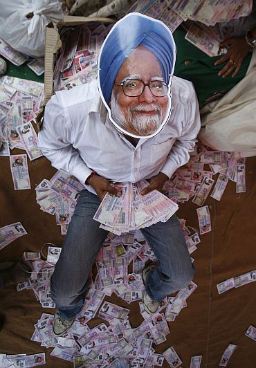 An activist wears a mask depicting Prime Minister Manmohan Singh