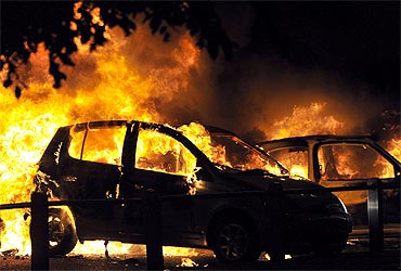 Cars burn on a street in Ealing, London, on Tuesday.