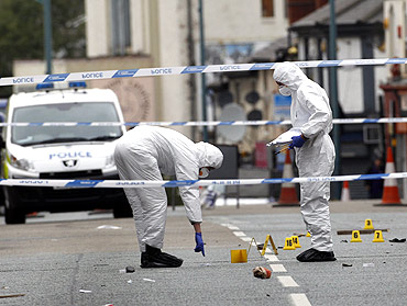 Forensics officers inspect the scene where three men were killed by a car in Winson Green area of Birmingham, central England
