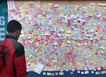 A youth looks at hundreds of messages of support from the community of Peckham posted on a looted storefront in southeast London
