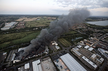 Smoke continues to rise from a Sony Warehouse which was destroyed by arsonists in Enfield in north London