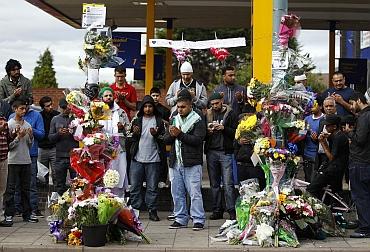 British Asians pray at the scene where three men were killed by a car during the recent rioting in the Winson Green area of Birmingham