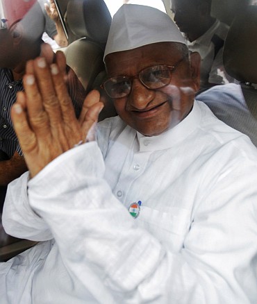 Social activist Anna Hazare waves from a car after being detained by the police in New Delhi