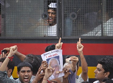 A Hazare supporter shouts anti-government slogans from a police vehicle after being detained