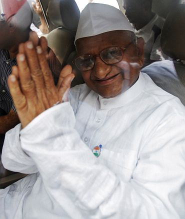 Anna Hazare gestures from a car after being detained by police in New Delhi on Tuesday