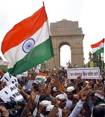 Supporters of Anna Hazare raise national flags during a protest march against corruption