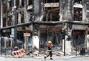 A fireman walks past the smouldering remains of a burnt out building after riots on Tottenham High Road in London.