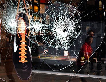A shoe hangs in the smashed window of the Nike store in Manchester, northern England, after the riots