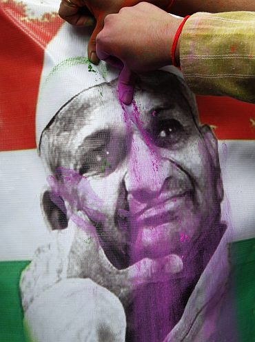 Supporters of activist Anna Hazare applies pink powder on the portrait of Hazare during the celebrations after Hazare ended his fast