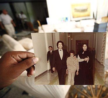 A Libyan shows a photograph of Muammar Gaddafi, his son Seif al Islam and his wife Safia at Hannibal's house in Tripoli August 30