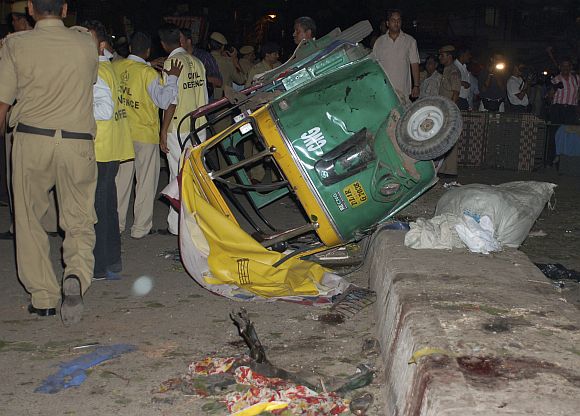 Onlookers stand at the site of one of the five bomb blasts that rocked New Delhi on September 13, 2008