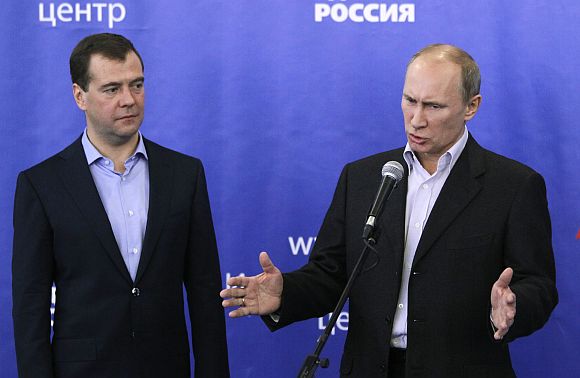 Russian PM Putin gestures as President Medvedev looks on during a news conference after voting closed in parliamentary elections in Moscow on Sunday