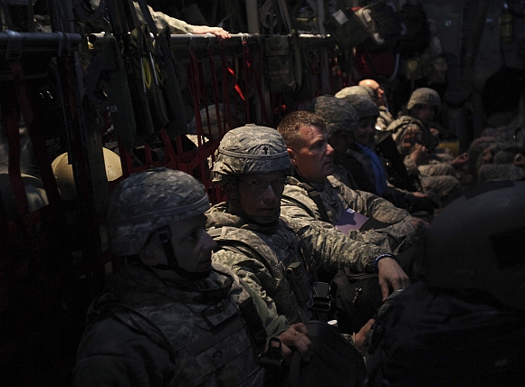 Members of the US military board sit in an Air Force C-130 transport plane after departing the Baghdad Diplomatic Support Center in Baghdad on December 15