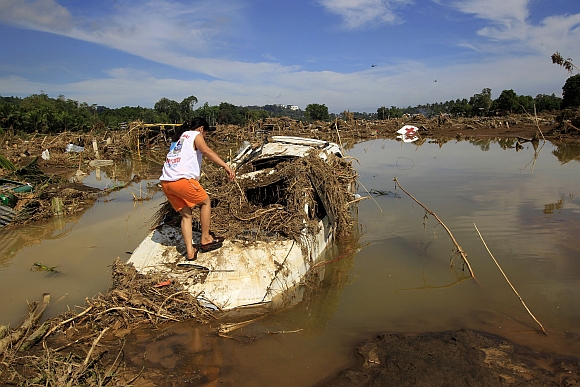 A woman inspects a submerged vehicle in a village hit by flashfloods brought by Typhoon Washi in Cagayan de Oro, southern Philippines