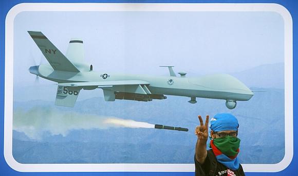 A Jamaat-e-Islami supporter flashes the victory sign in front of an image of drone, during a rally against drone attacks