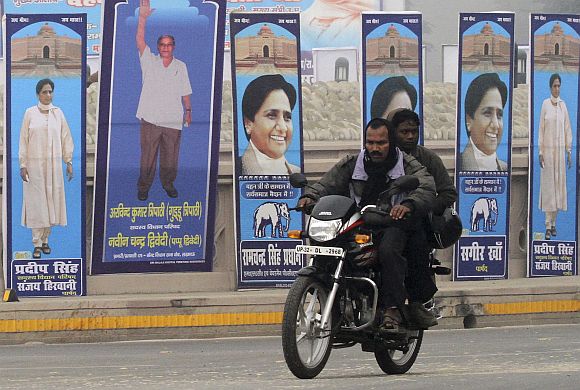 Men on motorcycle ride past Mayawati's picture in Lucknow as campaign season sets in UP