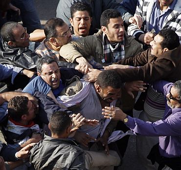 A pro-Mubarak supporter is held by anti-Mubarak demonstrators during clashes at Tahrir Square