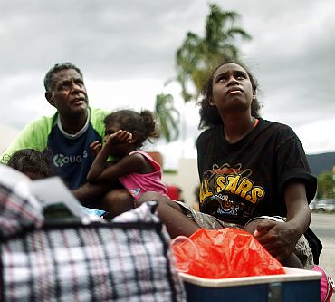 Local resident Selwyn Hughes sits with his daughter Roseanne, 13, outside an emergency cyclone shelter after it was declared full and the gate locked in the city of Cairns