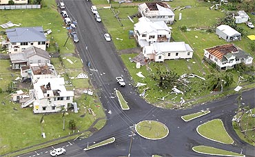 Houses with no roofs stand next to their undamaged neighbours after Cyclone Yasi