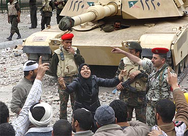 A female anti-government protester shouts slogans in front of army tanks near Tahrir Square in Cairo