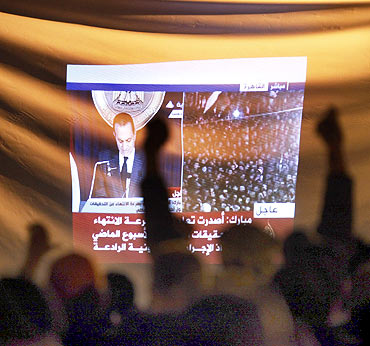 Demonstrators gesture as they listen to Egyptian President Hosni Mubarak's televised speech screened in Tahrir Square in Cairo