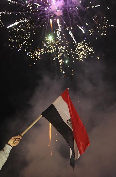 A man waves an Egyptian flag as fireworks explode during the celebration of the resignation of Egypt's President Hosni Mubarak