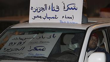 An Egyptian man holds a sign thanking Qatar-based channel Al-Jazeera as he celebrates the resignation of Egypt's President Hosni Mubarak