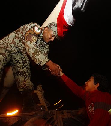 A young Egyptian shakes hands with an army officer atop a tank in Tahrir square in Cairo