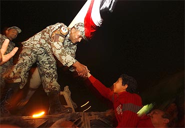 A young Egyptian is raised by his father to shake hands with an army officer atop a tank in Tahrir square in Cairo on Friday