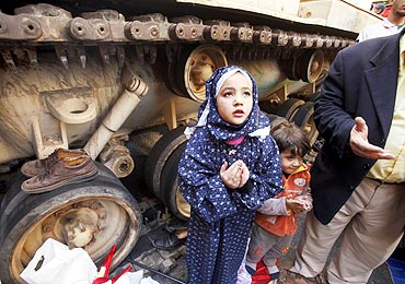 A girl attends Friday prayers in front of an army tank in Tahrir Square