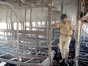 A file photo of a policeman inspecting the charred carriage of the Sabarmati Express