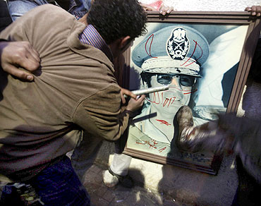 Anti-government demonstrators deface a picture of Libyan leader Muammar Gaddafi in Benghazi